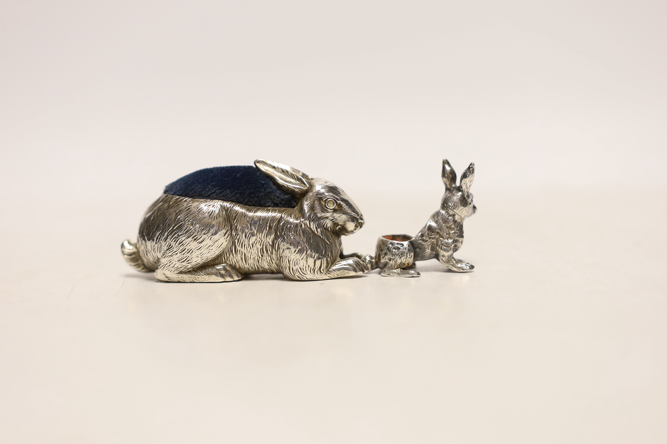 An Edwardian novelty silver pin cushion, modelled as a hare, ?M, Birmingham, 1907, length 67mm and a small white metal model hare pin cushion, lacking cushion.